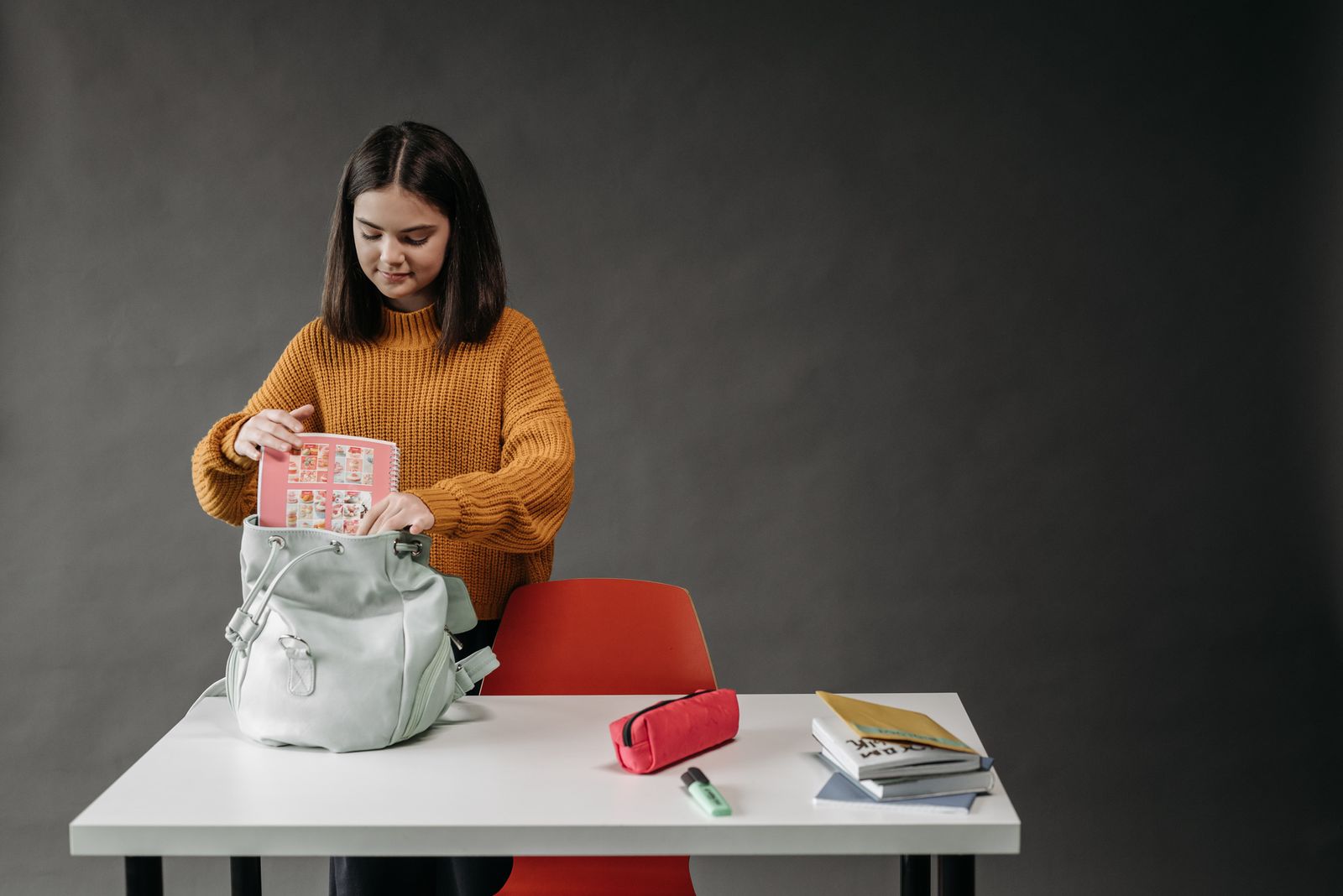 A student filling a backpack with school supplies